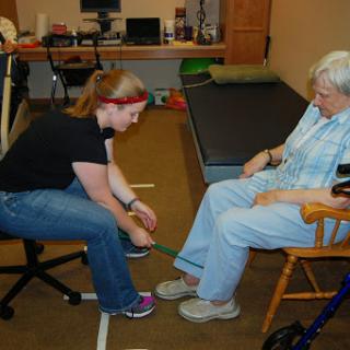 A therapist assists an elderly patient with an exercise or activity during a rehabilitation session.