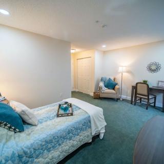 A cozy bedroom with a single bed, desk, and armchair.
