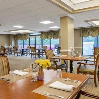 A spacious dining room with elegantly set tables and comfortable seating, featuring large windows and modern decor.
