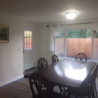 A dining room with a wooden table and chairs, featuring a window and door.