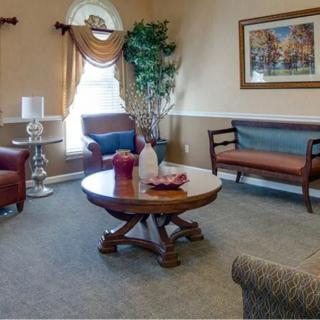 A cozy living room with a round wooden table, armchairs, and elegant decor.