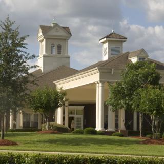 A grand building with prominent columns and twin towers amidst a landscaped setting.