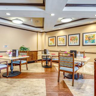 A cozy dining area with neatly arranged tables and chairs, featuring wall art and modern lighting.