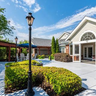 A well-maintained outdoor patio area featuring landscaped gardens, a modern building, and clear blue skies.