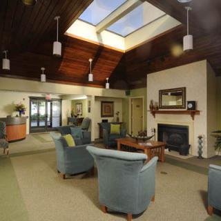 A cozy lobby with comfortable seating, a fireplace, and a skylight.