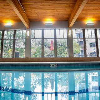A serene indoor swimming pool with large windows and reflective water.