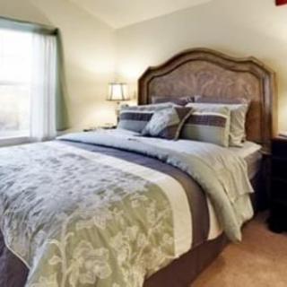 A cozy and well-decorated bedroom with a classic wooden headboard and elegant bedding.