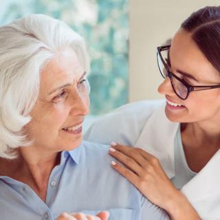 A healthcare professional providing support to an elderly patient.