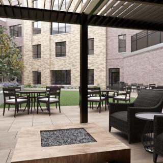 A cozy outdoor patio with seating and a fire pit, surrounded by an apartment building.