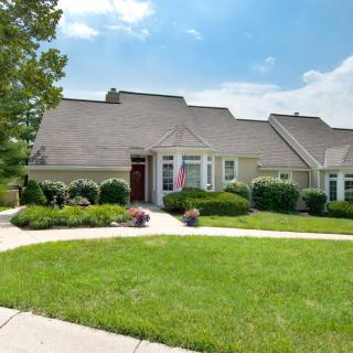 A suburban house with a well-maintained lawn and landscaping under a clear, sunny sky.