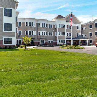 A modern multi-story building with well-maintained landscaping and a flagpole in the front.