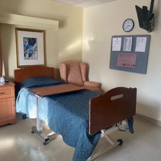 A hospital room featuring a bed, armchair, and wall decor.