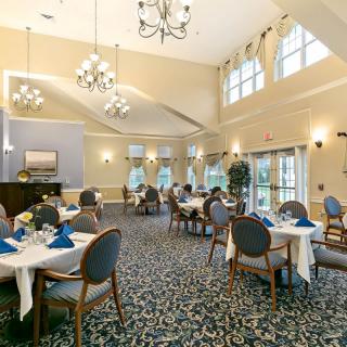 An elegant dining room with chandeliers, featuring neatly arranged tables and chairs.