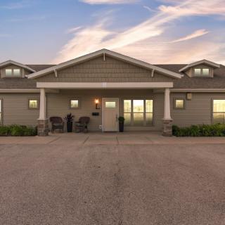 A residential building with a front porch and driveway under a sunset sky.