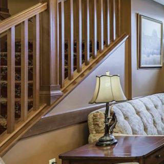 A cozy living room with a wooden staircase and an elegant table lamp on a side table beside a plush sofa.