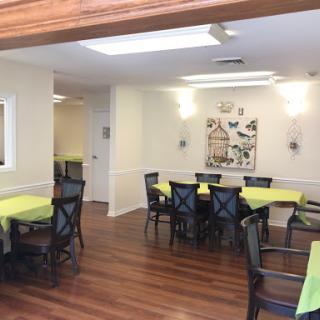 A bright and inviting dining area with green tablecloths and wooden flooring.
