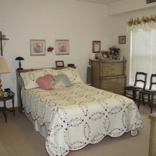 A cozy bedroom with a quilt-covered bed, wooden furniture, and charming decor.