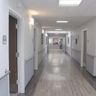 A well-lit hospital corridor with doors leading to various rooms.