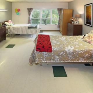 A spacious bedroom with two beds, a window, and various furnishings.