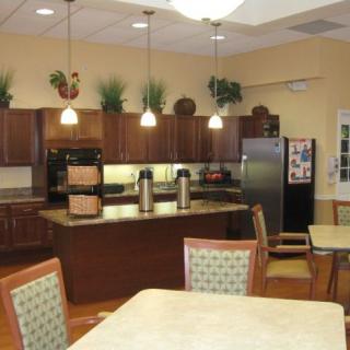 A modern kitchen interior with wooden cabinets, an island, chairs, and pendant lighting.
