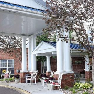 A building entrance with large columns, benches, and surrounding trees.