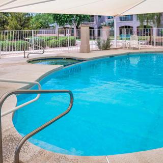 A serene outdoor swimming pool with a safety fence and shade umbrellas.