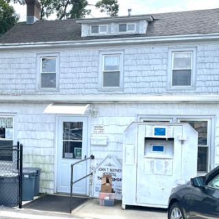 A two-story residential building with a white exterior and an entrance leading to a mailbox.