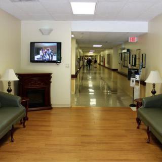 A hallway with sofas and lamps, featuring a television mounted on the wall.