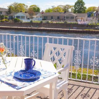 A charming patio setup by the waterfront with a table set for dining, offering a serene river view.