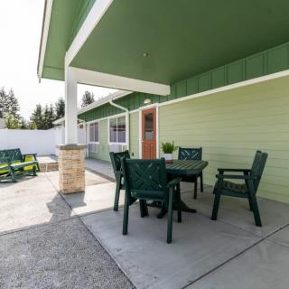 A cozy backyard patio with a set of green outdoor chairs and a table under a covered area.