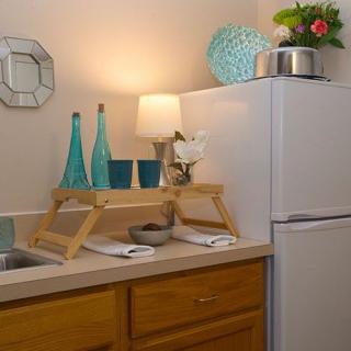 A well-decorated kitchen counter with teal bottles, a small lamp, and flowers next to a refrigerator.