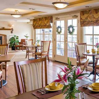 A cozy dining room with elegantly set tables and natural lighting from large windows.
