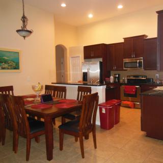 A modern open-concept kitchen and dining area featuring wooden furniture and stainless steel appliances.