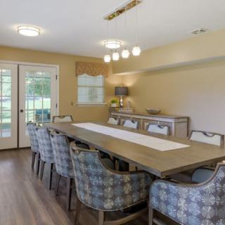 A modern dining room with a large wooden table surrounded by patterned chairs.