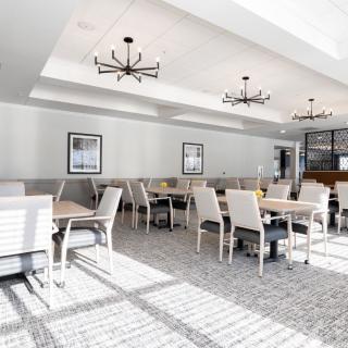 A modern restaurant dining room with elegant chandeliers and ample natural light.