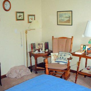 Cozy bedroom corner with a rocking chair, tables, and wall decor.