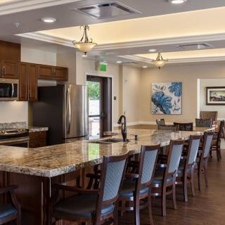 A modern kitchen and dining area with a long table and granite countertops.