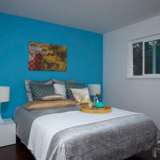A modern bedroom with a blue accent wall and decorative pillows.