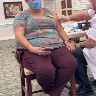 A healthcare worker administering a vaccine to a seated individual wearing a mask.