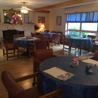 A cozy dining area with well-arranged tables and chairs, adorned with simple decorations and natural light from the windows.