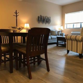 A cozy living room featuring a dining area with a wooden table and chairs, a sofa, and elegant lighting.