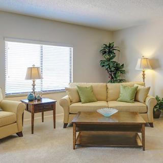 A cozy living room with a beige sofa, green cushions, and warm lighting.