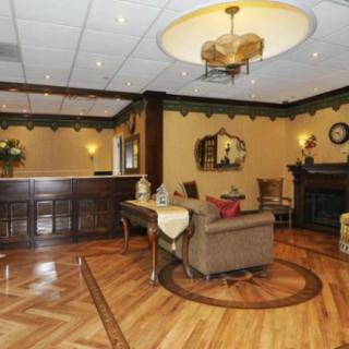 A classic hotel lobby with a warm wooden floor, cozy seating, and elegant chandeliers.