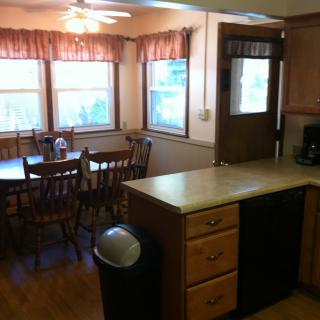A cozy kitchen and dining area with wood cabinets and a dining table near large windows.