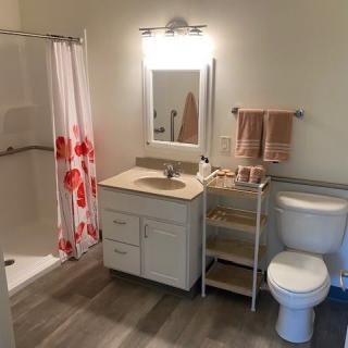 A clean and organized bathroom with a shower, sink, and toilet.