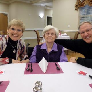 A group of three people enjoying a meal together at a dining table.