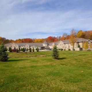 A scenic view of a large building surrounded by a lawn and colorful autumn trees under a clear sky.