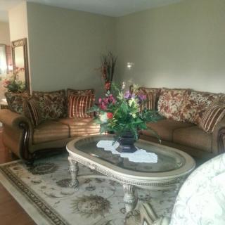 A cozy living room with a patterned sofa set and a decorative floral arrangement on the coffee table.