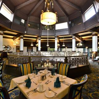 An elegant restaurant interior with a beautifully set table and a grand chandelier.