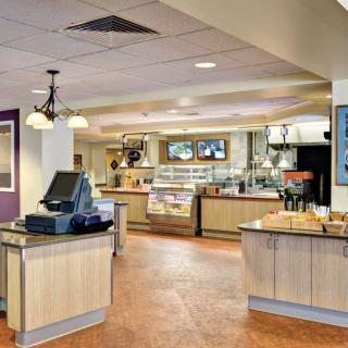 Modern cafeteria interior with a food service counter and cash register.